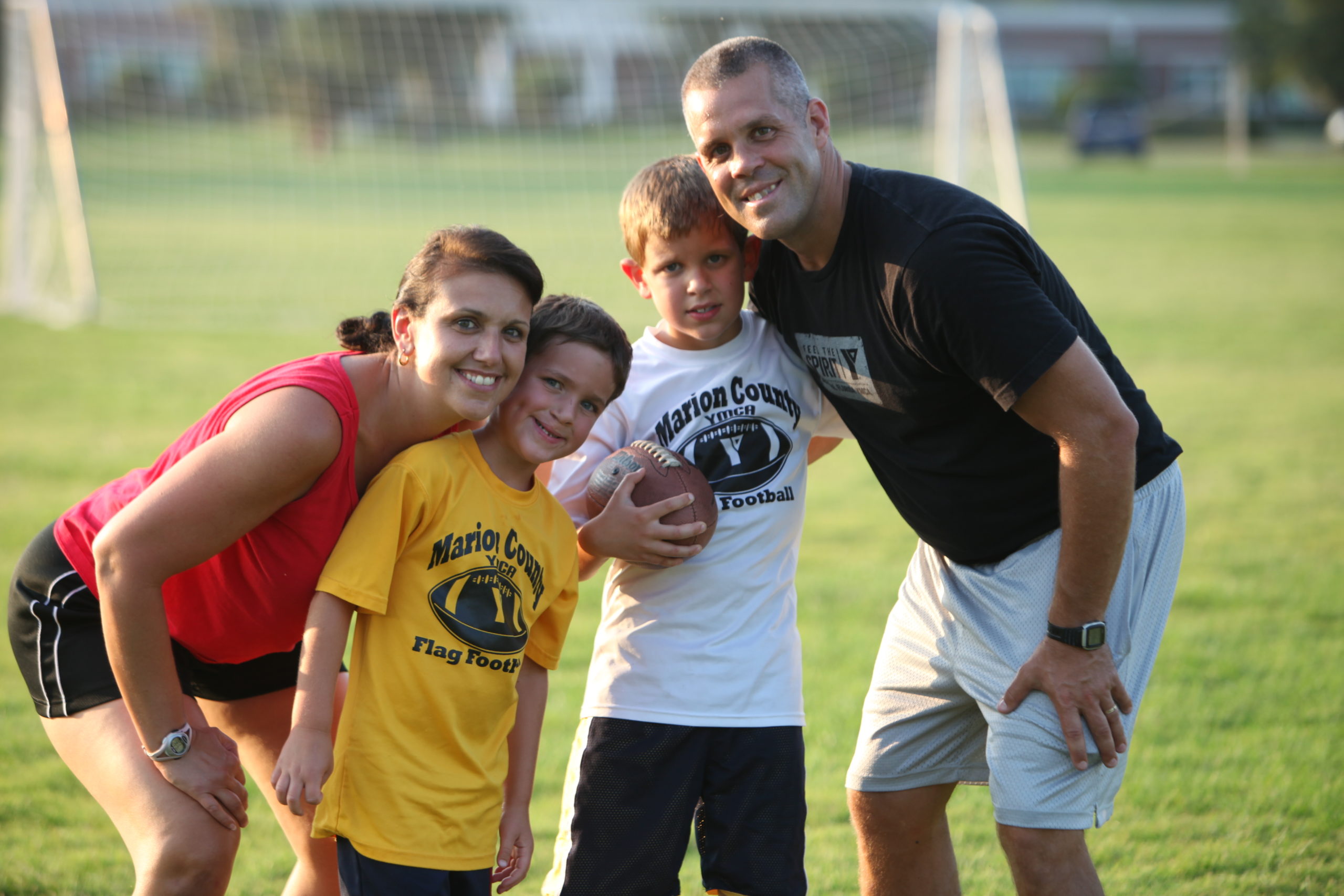 Mom, dad and sons playing football outside