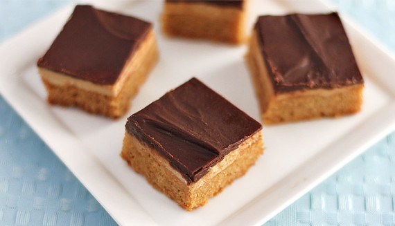 Nut butter and chocolate protein bars on square plate on top of blue tablecloth