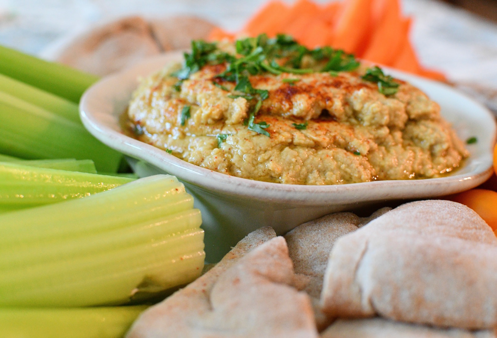 Hummus in a bowl with celery and carrots