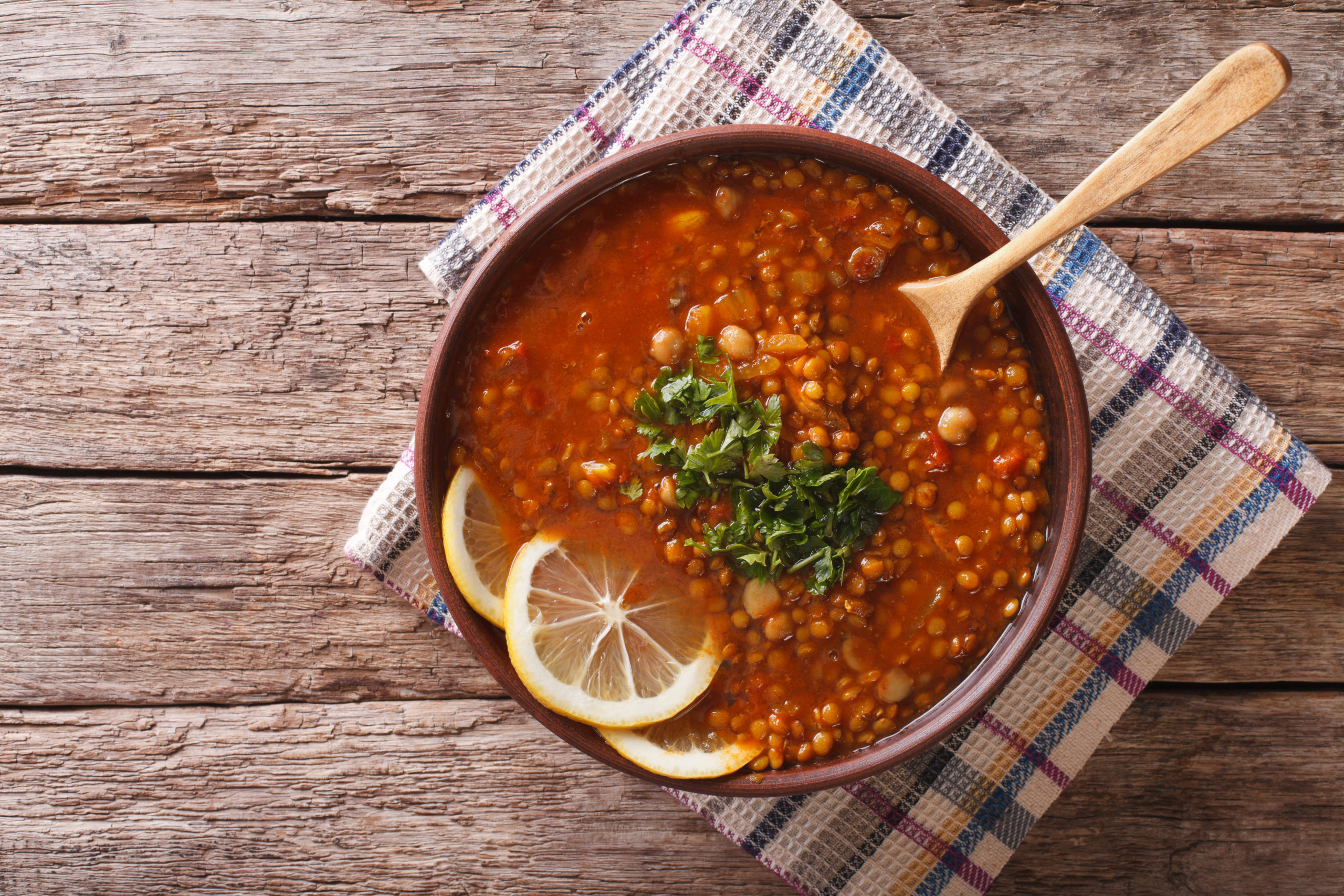 Lentil and chickpea soup in pot with oranges and topped with parsley