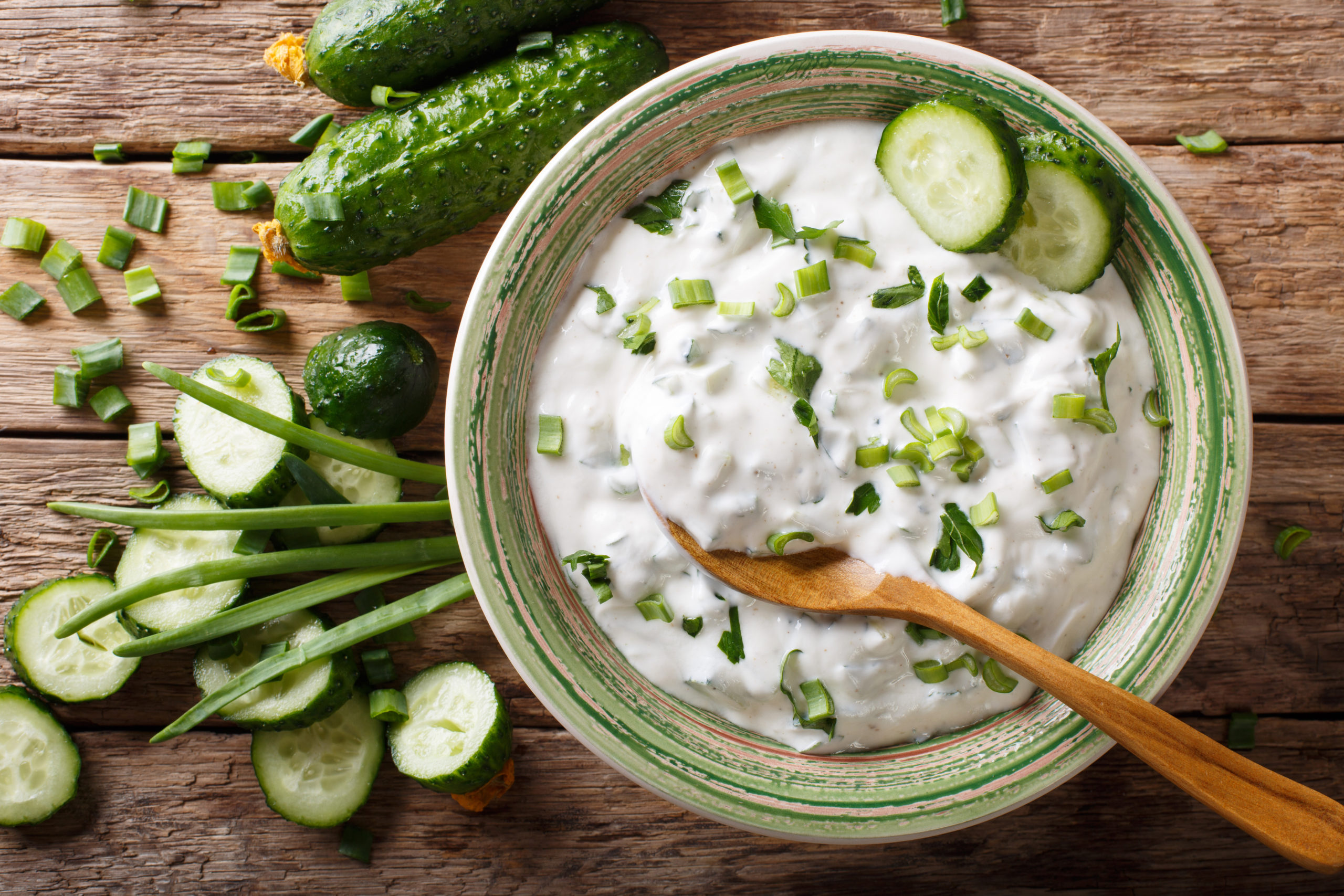 Herbed yogurt dip in a green bowl with wooden spoon and dills
