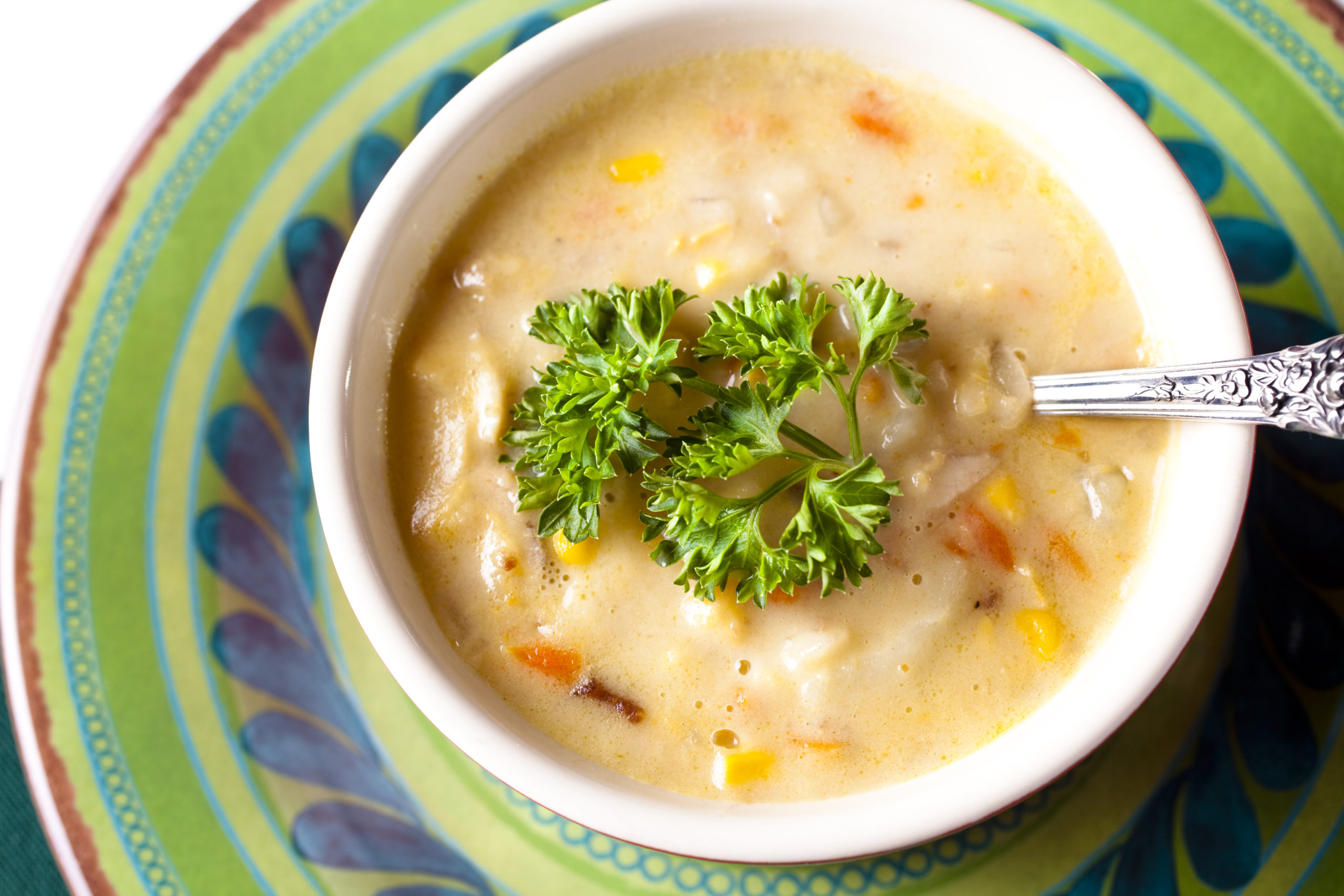 Corn chowder in a white bowl with a spoon