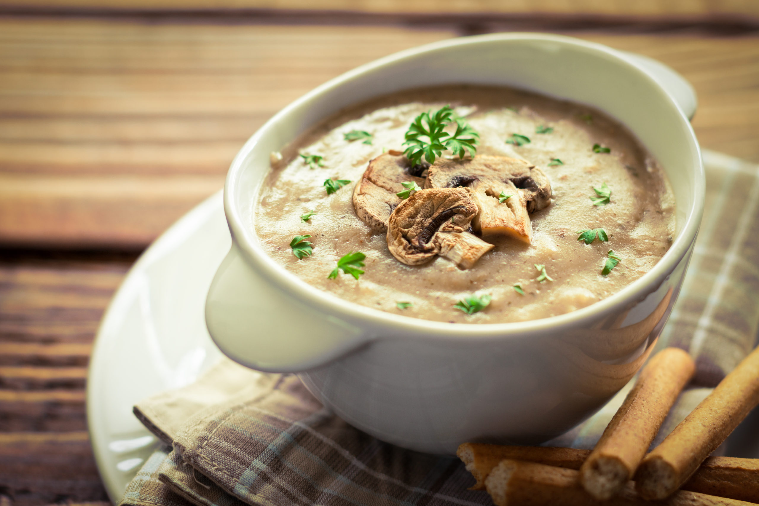 Mushroom soup in bowl on top of wooden table
