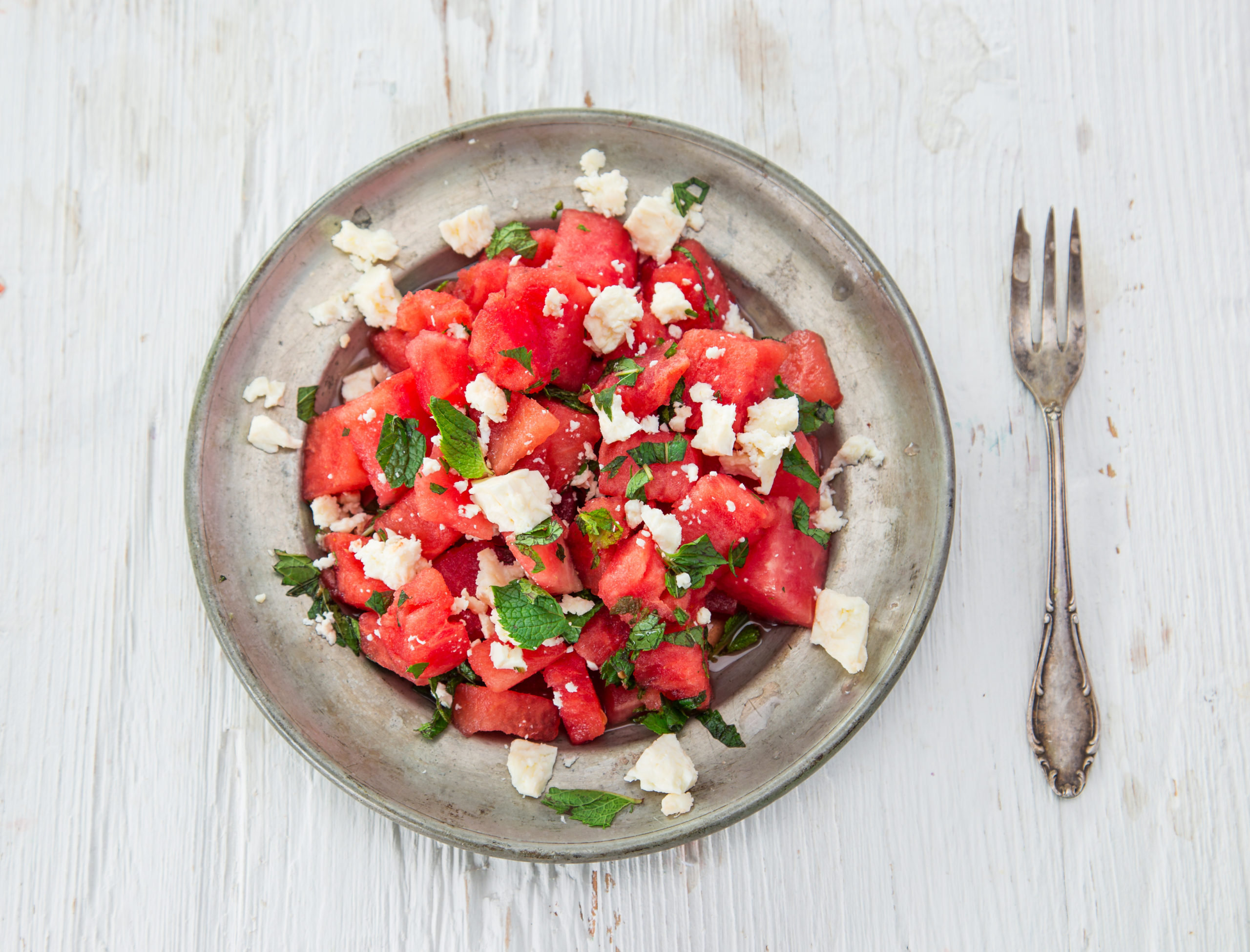 Watermelon arugula salad on a plate next to a fork