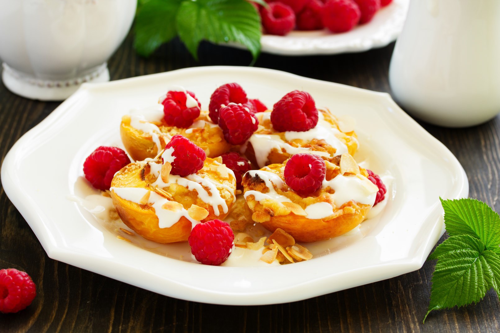 Grilled peach halves on white plate with raspberry yogurt sauce and topped with raspberries