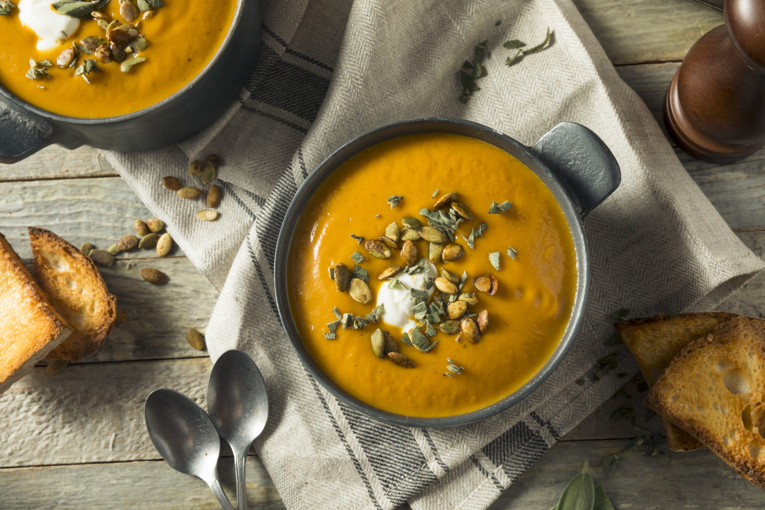 Curried carrot and squash soup in bowls with squash seeds on top