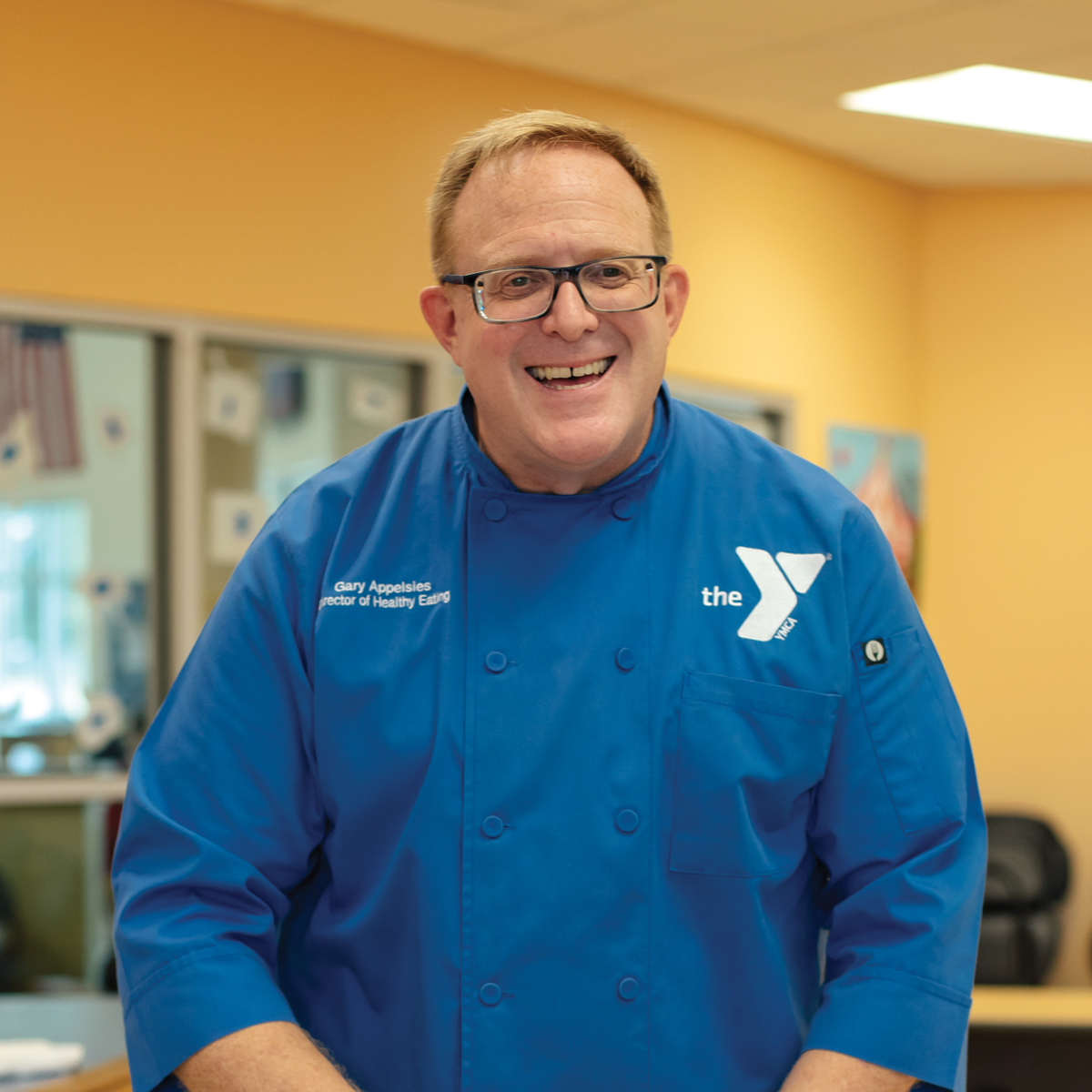 Gary Appelsies wearing a blue chef's apron coat with the YMCA logo on it
