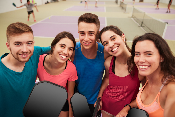 A group of friends makes a selfie with pickleball paddles