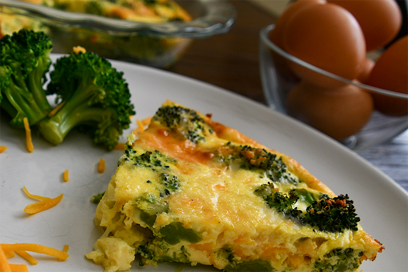 Image of broccoli quiche on a plate next to a broccoli with cheese on top