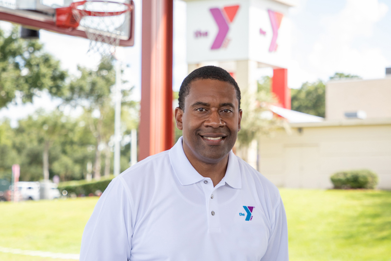 Photo of Kevin Bolding wearing white YMCA golf shit outside art the Frank DeLuca Sportsplex
