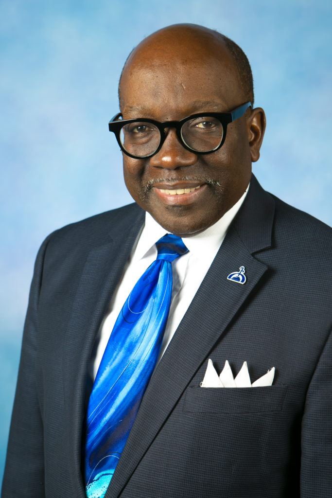 Headshot of Reginald B. McGill in a suit against a blue background