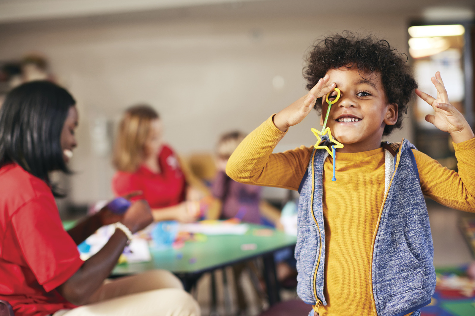 Boy standing holding a star wand while smiling in child care