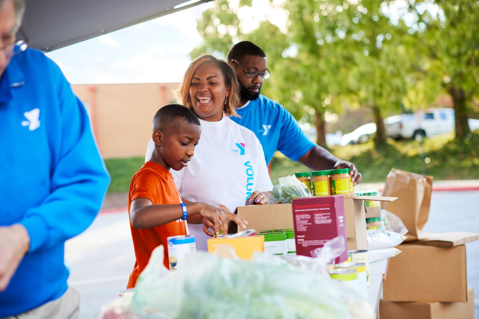 YMCA family of volunteers helping out at a food drive while wearing YMCA t-shirts