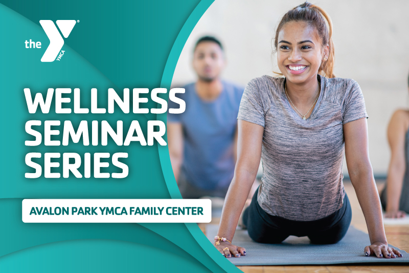 Image of a woman smiling while doing cobra pose on a yoga mat in yoga class with the words Wellness Seminar