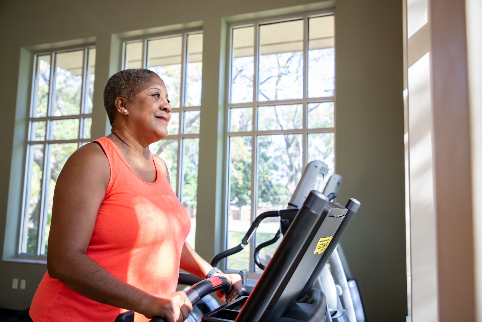 Image of Chondra on a treadmill at the Dr. P. Phillips YMCA while surrounded by windows and the sun shining on her face as she smiles