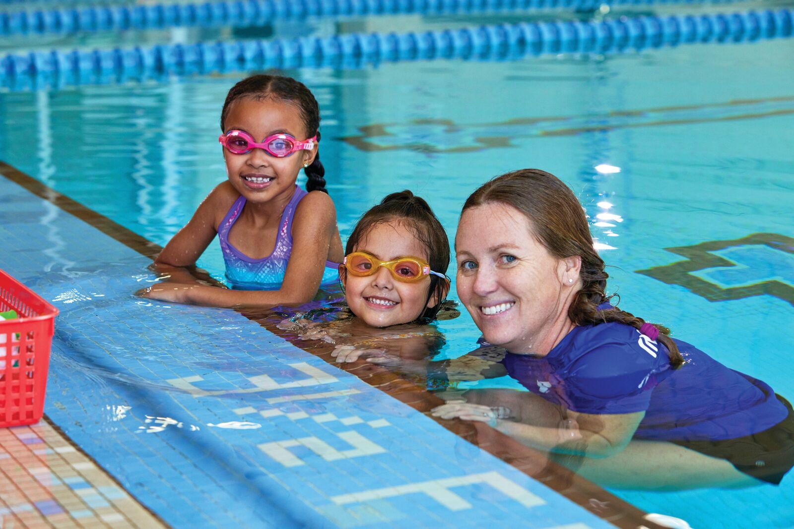Instructor in swimming pool with two young students for swim lessons