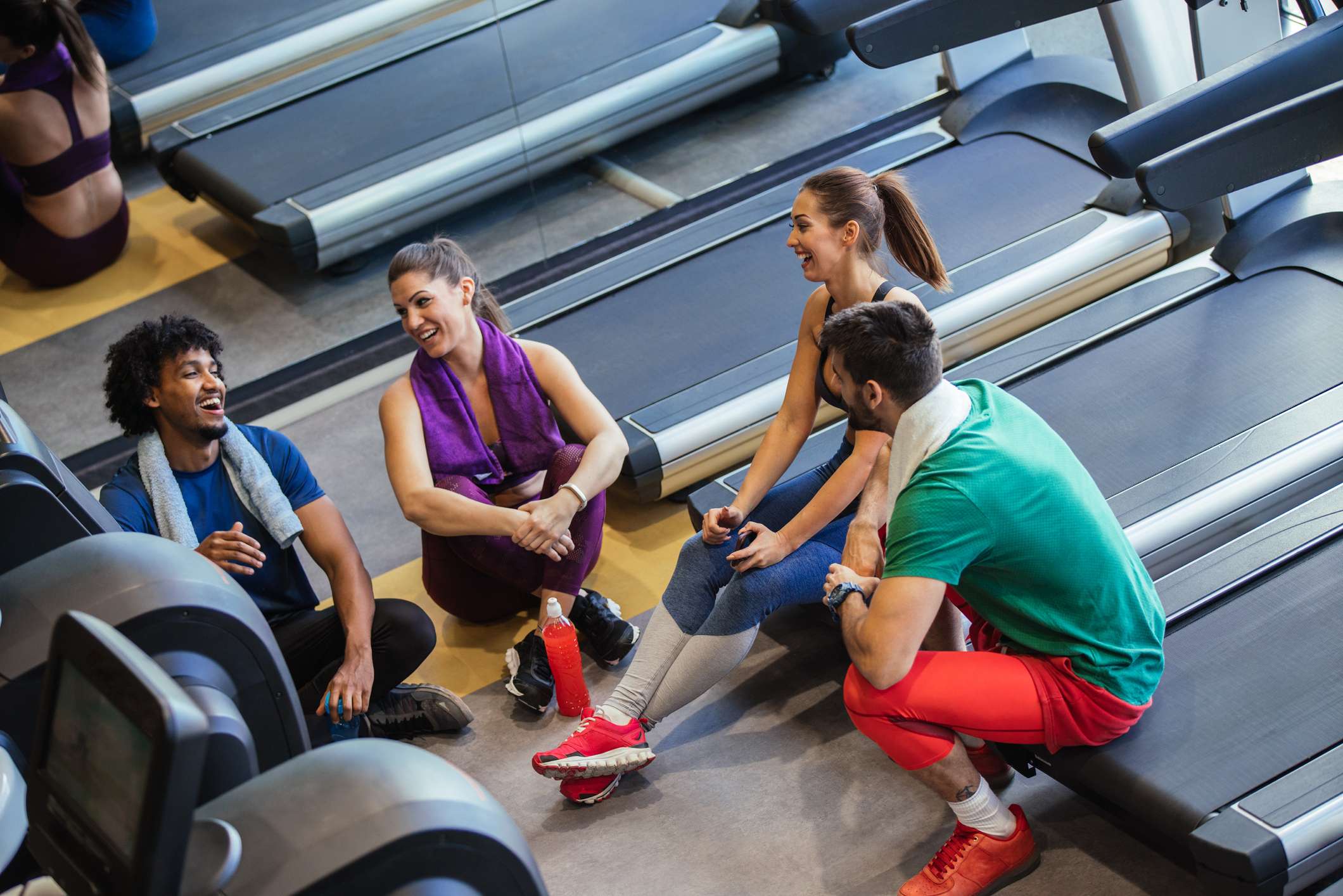 Group of young adults in gym together by the treadmills