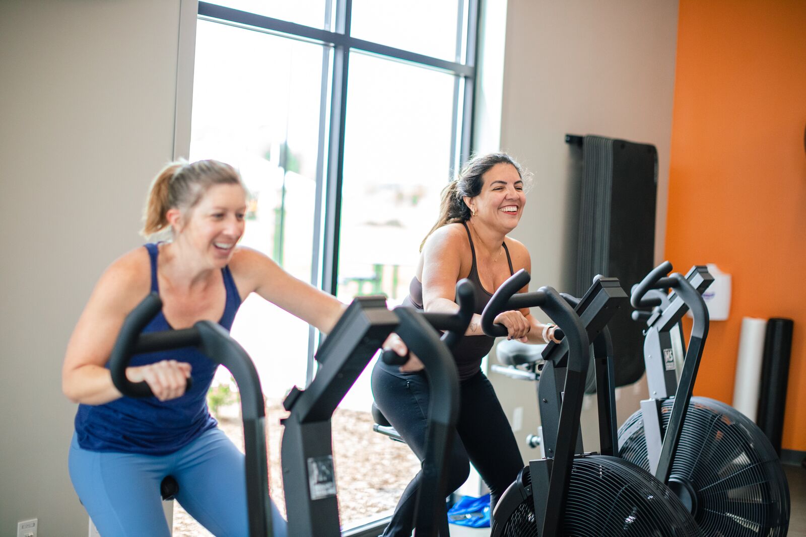 Two women on assault bikes at the YFX classes