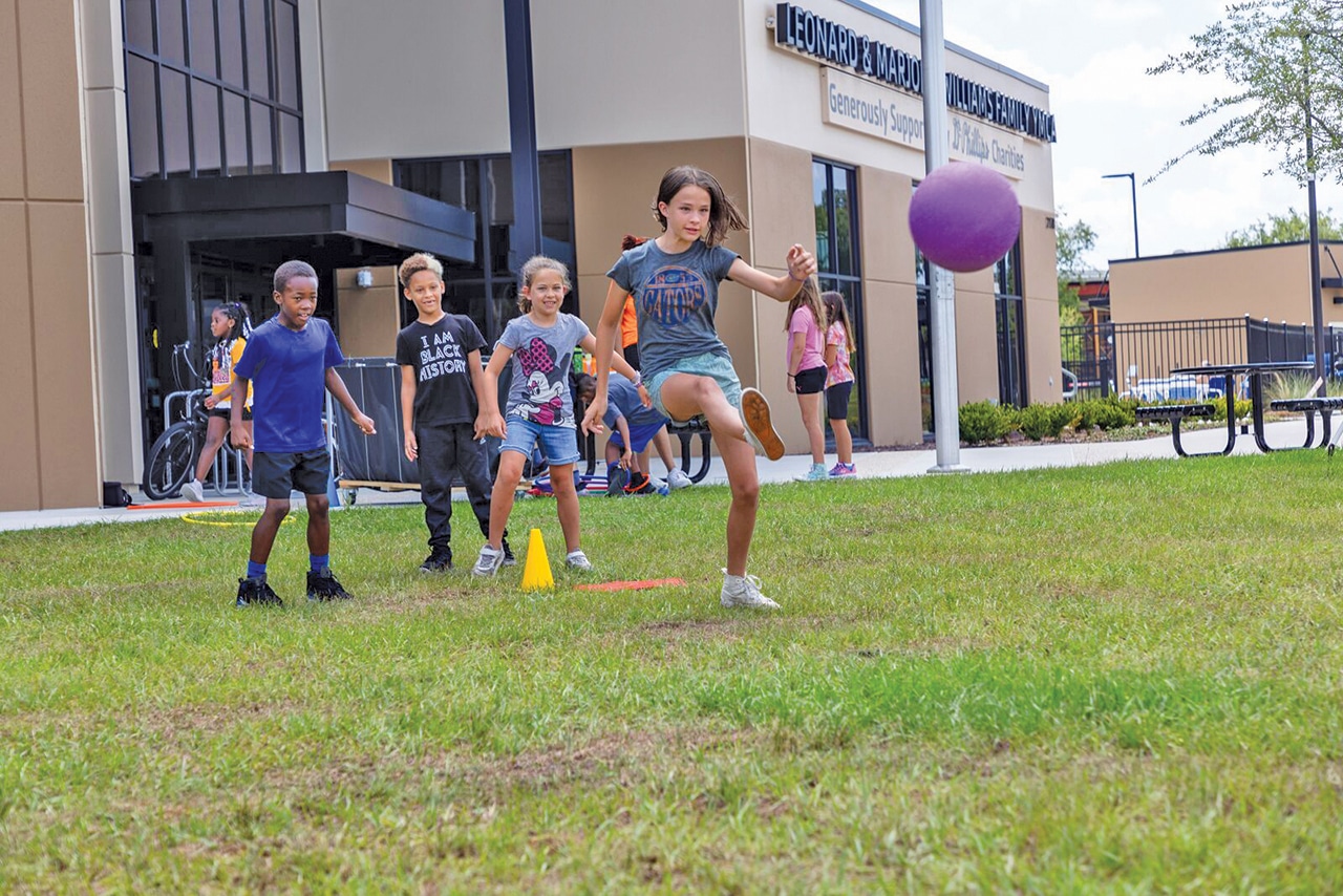 A group of kids playing kickball in the field at the YMCA