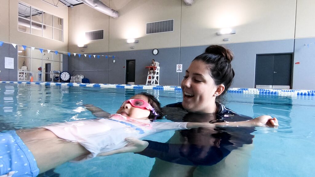Child floating on back with swim lesson instructor during private swim lesson at the YMCA of Central Florida