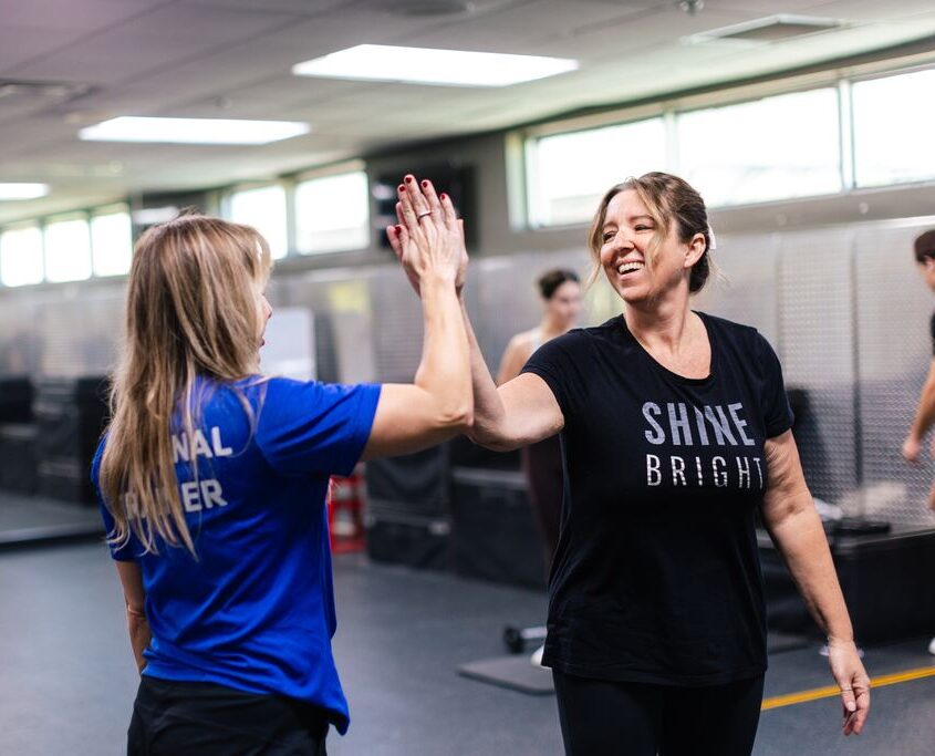 A woman inside a gym high-fiving her personal trainer at the Downtown Orlando YMCA