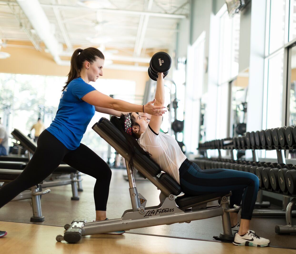 Personal trainer helping a YMCA member with doing an incline dumbbell press correctly