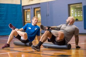 Two men stretching together using rollers during a personal training session at the YMCA