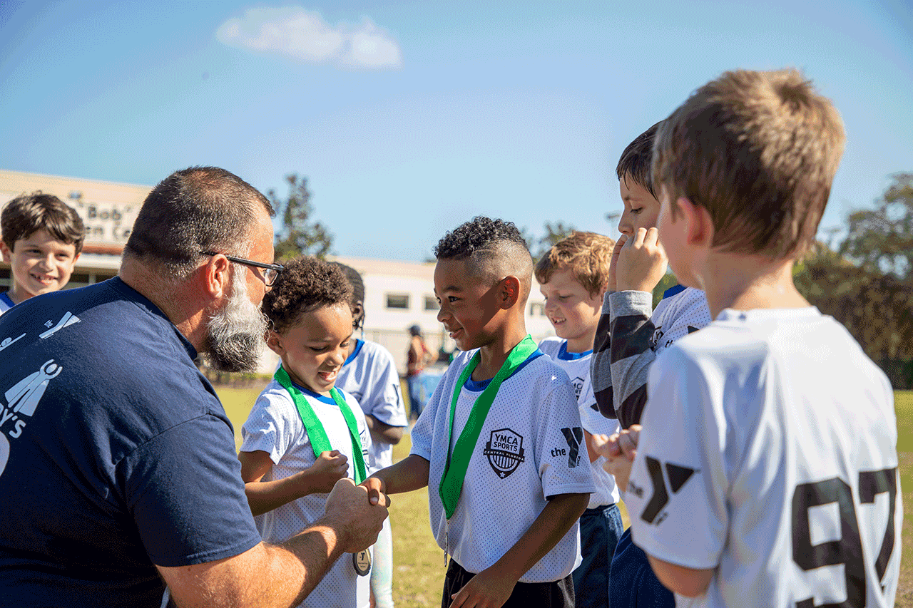 Child receiving a youth sports award from his coach at the YMCA