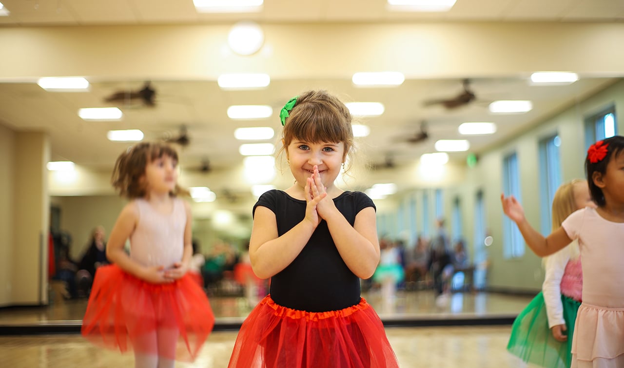 A little girl in a red tutu taking a dance ballet class at the YMCA